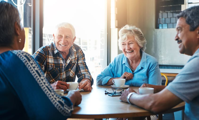 A group of people around a table laughing and drinking tea