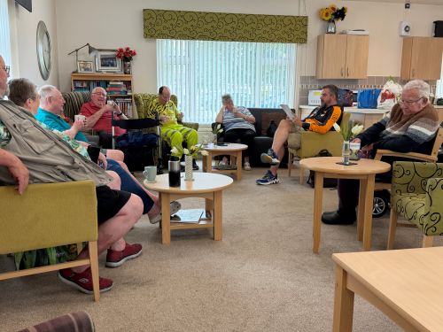 A group of people in circle, drinking tea and reading newspapers