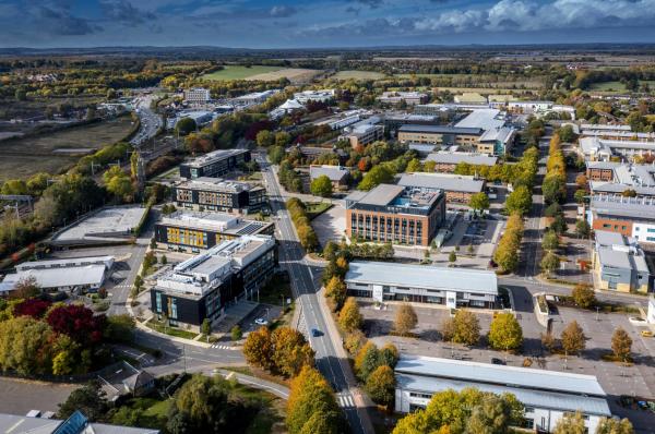 An aerial view of Milton Park, a science park in Oxfordshire, featuring labs, office buildings and tree-lined streets.