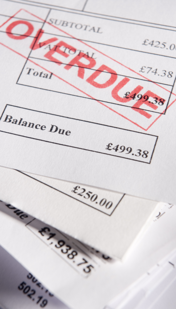 Close-up of several paper invoices with printed amounts and an ‘OVERDUE’ stamp in red across the top document.