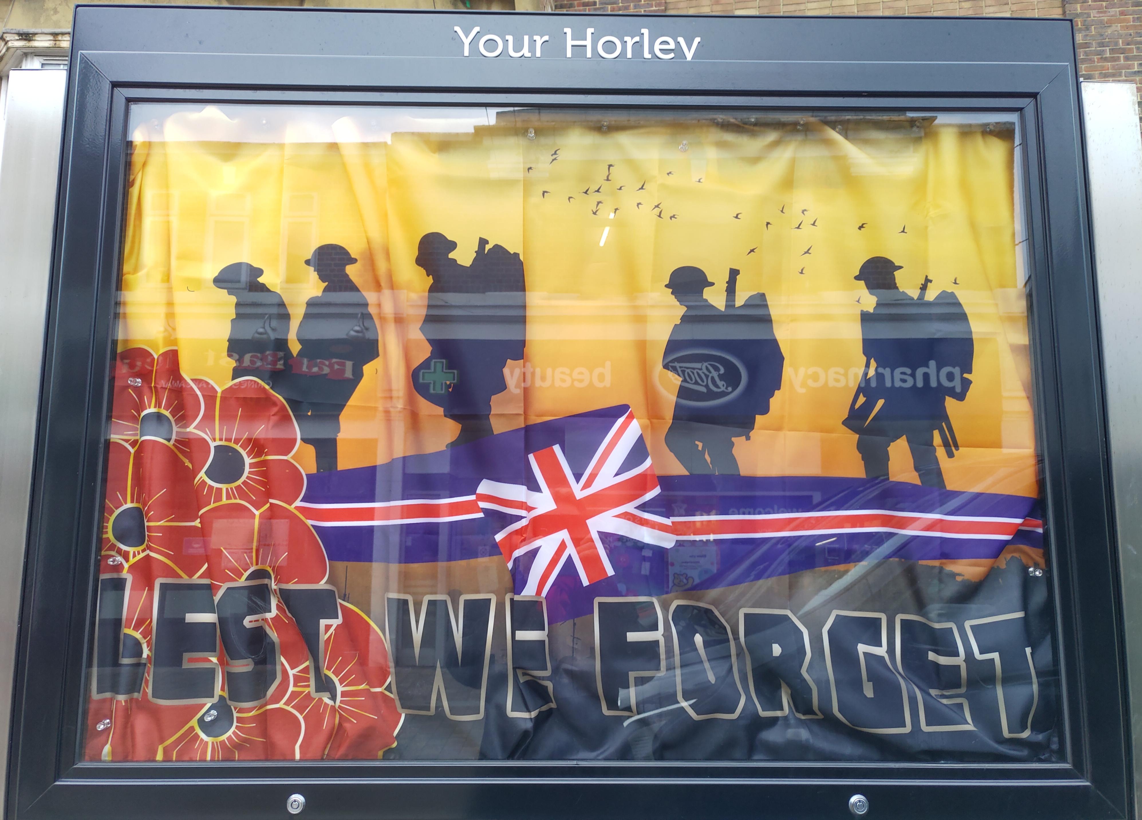 A picture of the Horley Town Noticeboard in the high street containing a flag for Remembrance Day.  