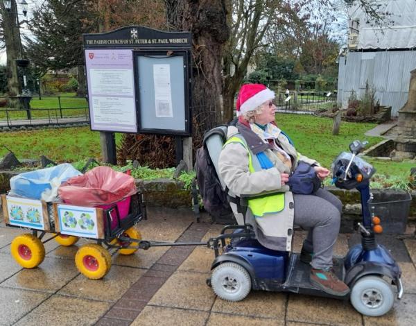 Alexia wearing Christmas hat riding her litter picking buggy by St Peters church in Wisbech