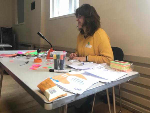 a person sitting behind a desk with badges, pens paper etc