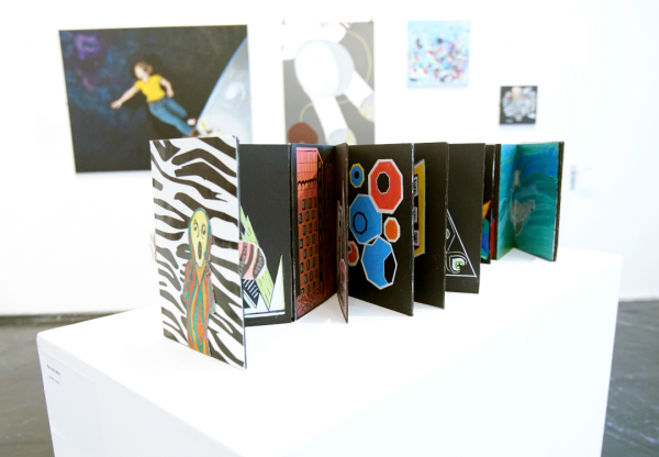 An artwork which is a book opened out with colourful paintings and patterns inside