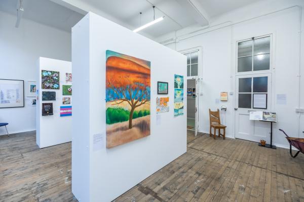 A photo of the Out of Sight Out of Mind exhibition with a large painting of a tree.
