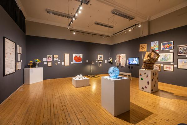 A photo of the Out of Sight Out of Mind exhibition with many sculptures in the room and artwork on the walls.