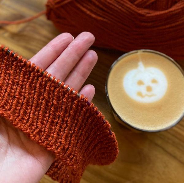 Knitting in a burnt orange and a hot drink with a pumpkin in latte art