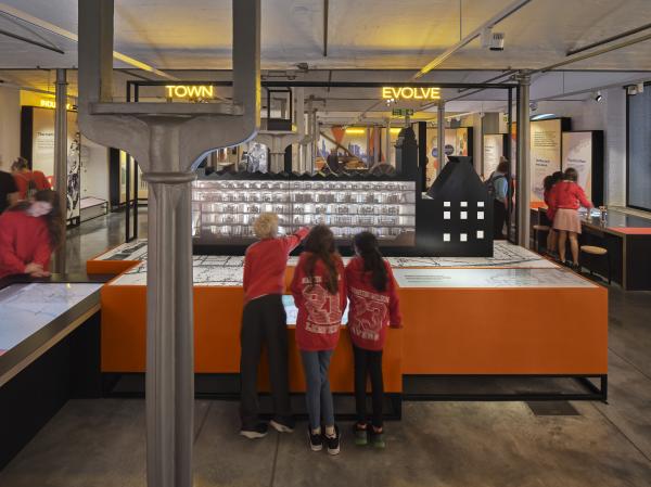 A group of children inside an exhibition, touching the interactives