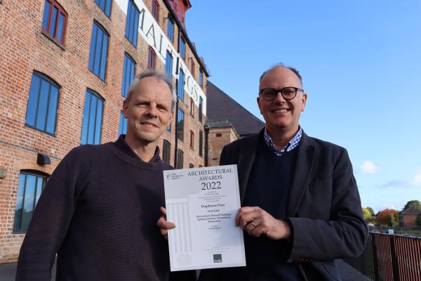 Two men holding an award certificate. 