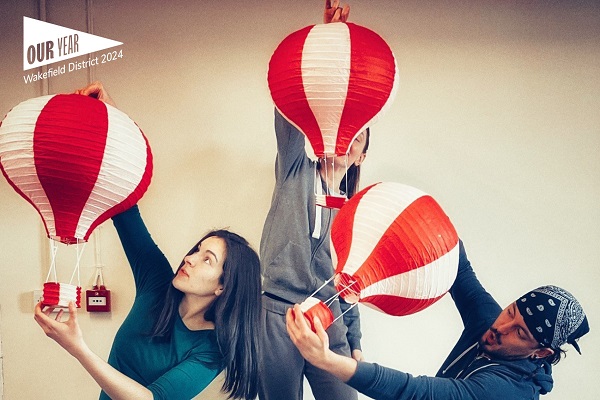 Image shows three people holding mini hot air balloons