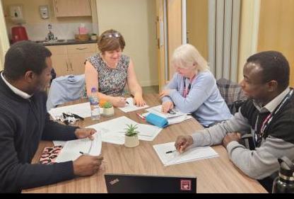 Group of workers sat around a table taking notes.