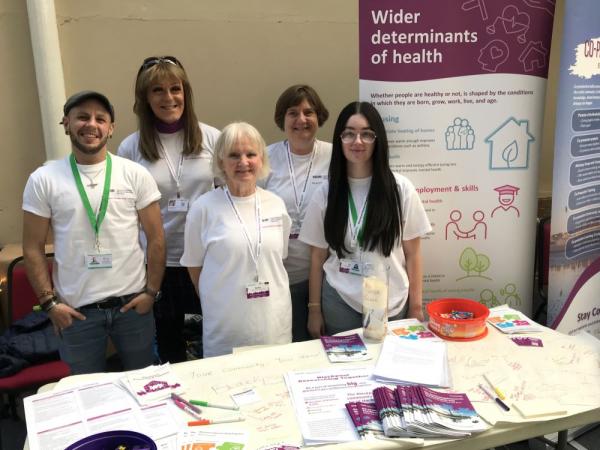 Blackpool Researching Together team members at an event standing with a table and banner.