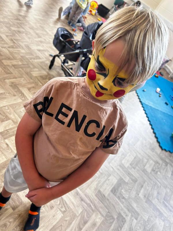 Image of young child wearing red and yellow face paint in the style of pokemon character pikachu.