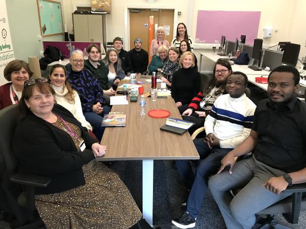 Blackpool Researching Together and HDRC Cumberland colleagues all gathered in around a table in an office environment.