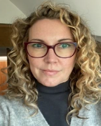 Headshot of woman with glasses and curly blonde hair.
