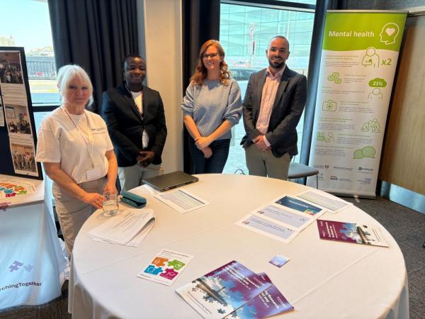 Two men and two women stood in front of an event table.