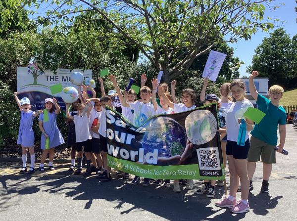 A group of children waving arms and holding a banner with the words save our world