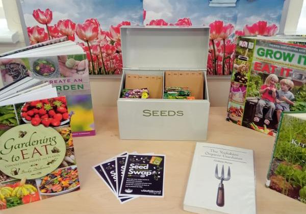 A number of books on the subject of gardening around a metal box with the words seeds containing seed packets