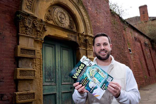 A photo of Councillor Michael Graham standing with the Voices of Westgate comic book in front of the historic green door on Westgate