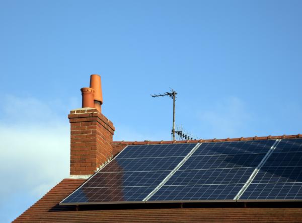 A photo of a roof with a chimney, aerial and some solar panels