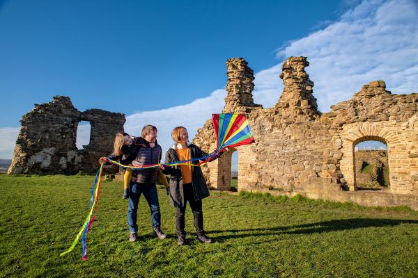 Two adults and a child on a sunny and breezy day at Sandal Castle
