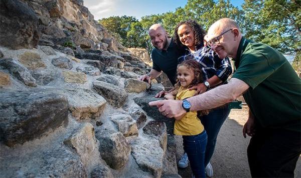 A volunteer guide showing a family around Pontefract Castle