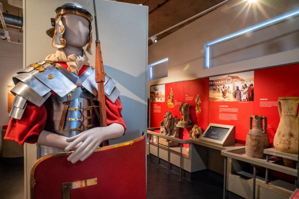 The Roman gallery at Castleford Museum, featuring replica armour in the foreground and stonework in the background.