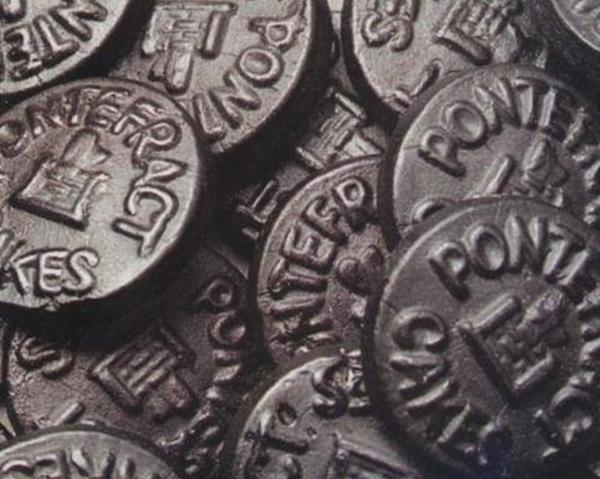 Black stamped circular Pontefract Cakes laid on top of one another.