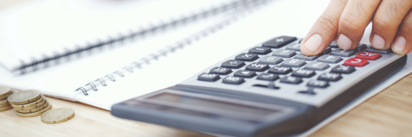 close up image of fingers on a calculator and papers in background