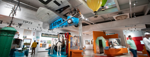 interior of a colourful museum with plane and hot air balloon models hanging from ceiling