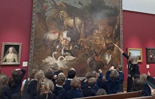 children all look at a large oil painting in a museums as part of a school outing