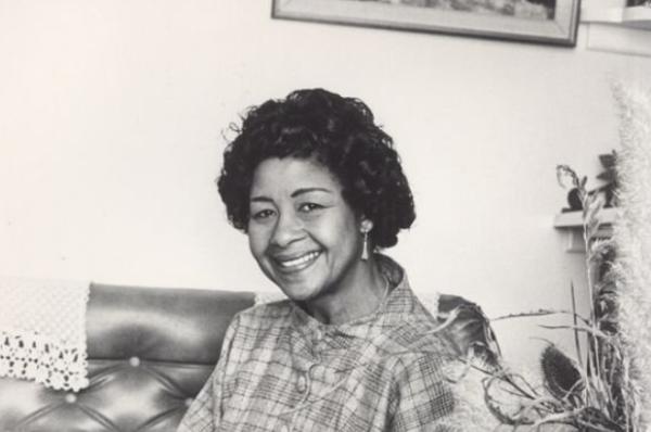 black and white photo of a smiling Black woman in a sitting room