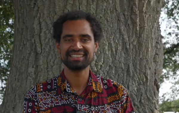 storyteller Marcus Fagon stands beside a tree smiling