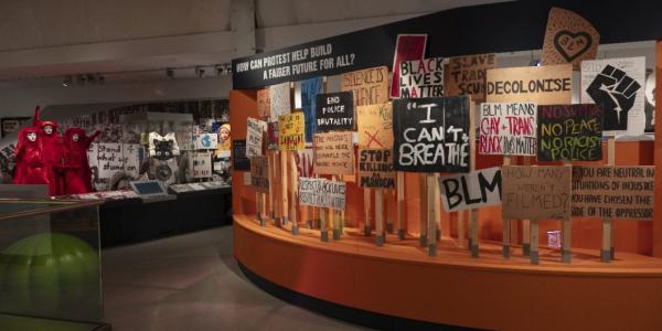 interior of M Shed. curved display on history of protest. plaques on wooden sticks with messaging from the Black Lives Matter protest in Bristol in 2020