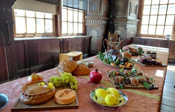 A tudor banquet table in a museum with fake food stuffs on table