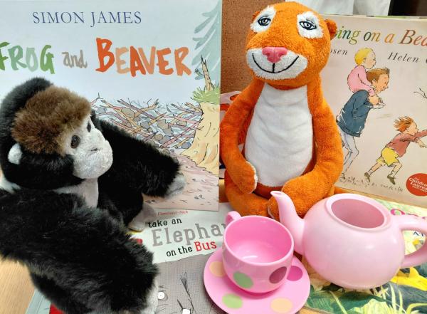 a tiger and gorilla soft toy amongst some tea cups and children's books