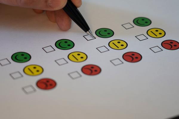 image of a feedback from using smiley faces . Hand with pen poised