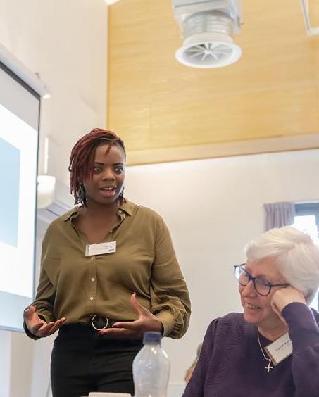 A young black woman expressively talking to an older white woman who is smiling. 