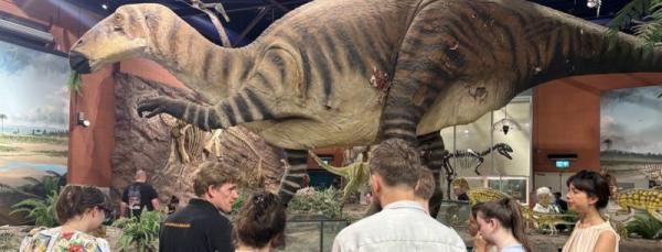 People in front of a scale model dinosaur in a museum