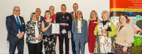 A group of people standing in a line. One of them in the middle is holding up a certificate. 