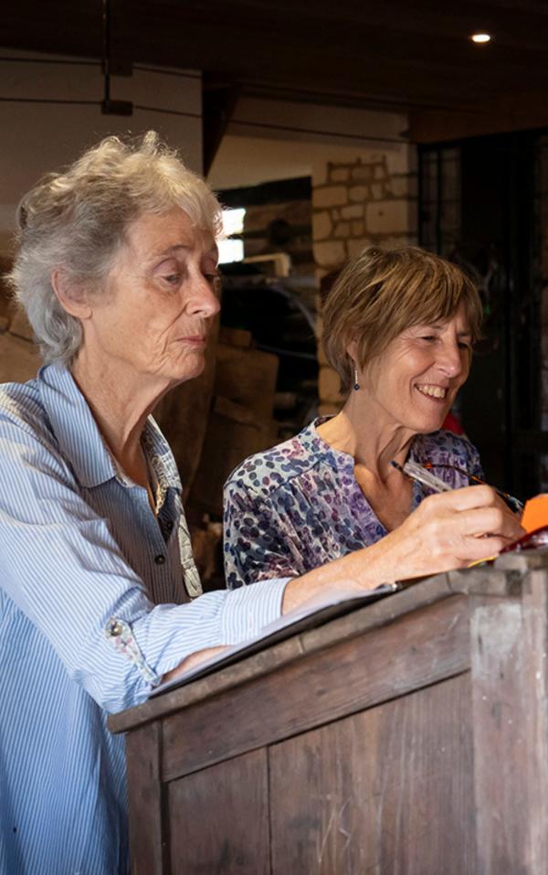 Two women talking and leaning over a desk