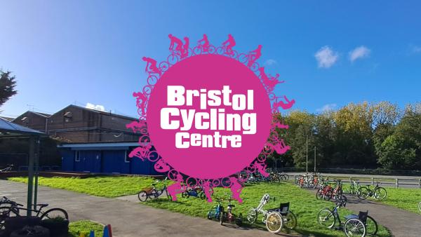 A picture of Bristol Cycling Centre with blue skies green grass, the blue containers full of bikes and inclusive biukes and handcycles out ready to be used.