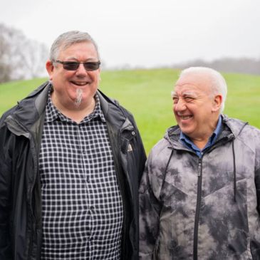Two older people, standing together and laughing