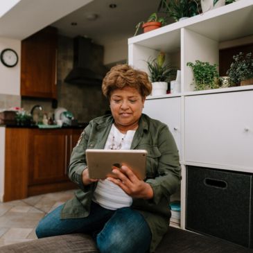 A person kneeling on the floor holding a tablet computer