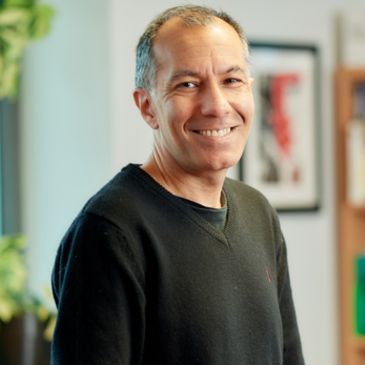 A person (Kapil Sayal) wearing a black jumper is smiling at the camera