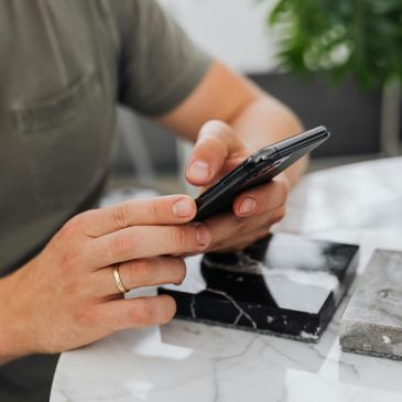 A person using both hands to hold a mobile phone. Only the hands and phone are visible