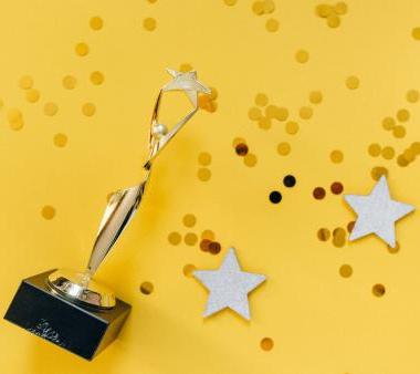 A gold trophy with glitter and stars on a yellow background