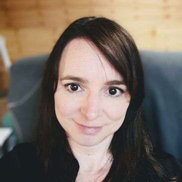 A person with long dark hair is smiling at the camera