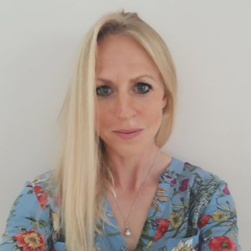 A person with long blonde hair is smiling at the camera