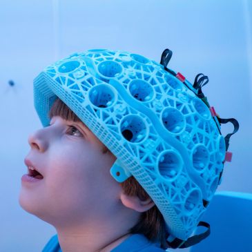 A child wearing a blue cap with holes in is looking upwards